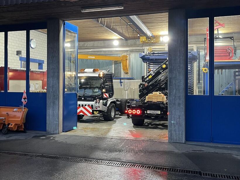 Werkstatt an der Schluchenstrasse bei Dämmerung, Kranfahrzeug in der offenen Halle
